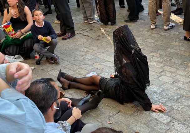 Una joven con un pañuelo en la cabeza está sentada en el suelo esperando a la fraternidad.