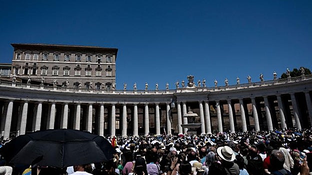 Multitud de fieles escuchando a Francisco en la plaza de San Pedro, algunos se protegen del calor con paraguas