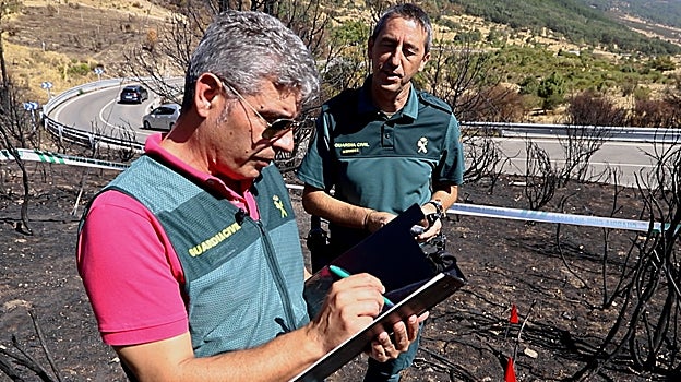 El agente Díaz Martín y un compañero apuntan datos en el 'epicentro' del incendio, cercano a la carretera