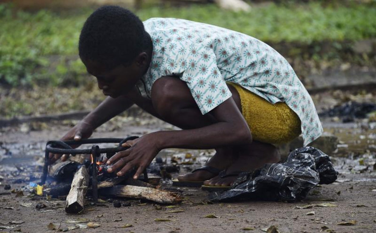 Un niño enciende un fuego para cocinar en un campamento para desplazados en Ihuike, Nigeria