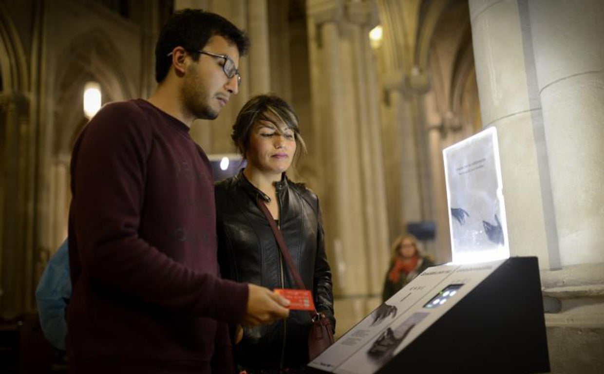 Dos feligreses hacen un donativo con tarjeta en un cepillo electrónico de la catedral de la Almudena, en Madrid