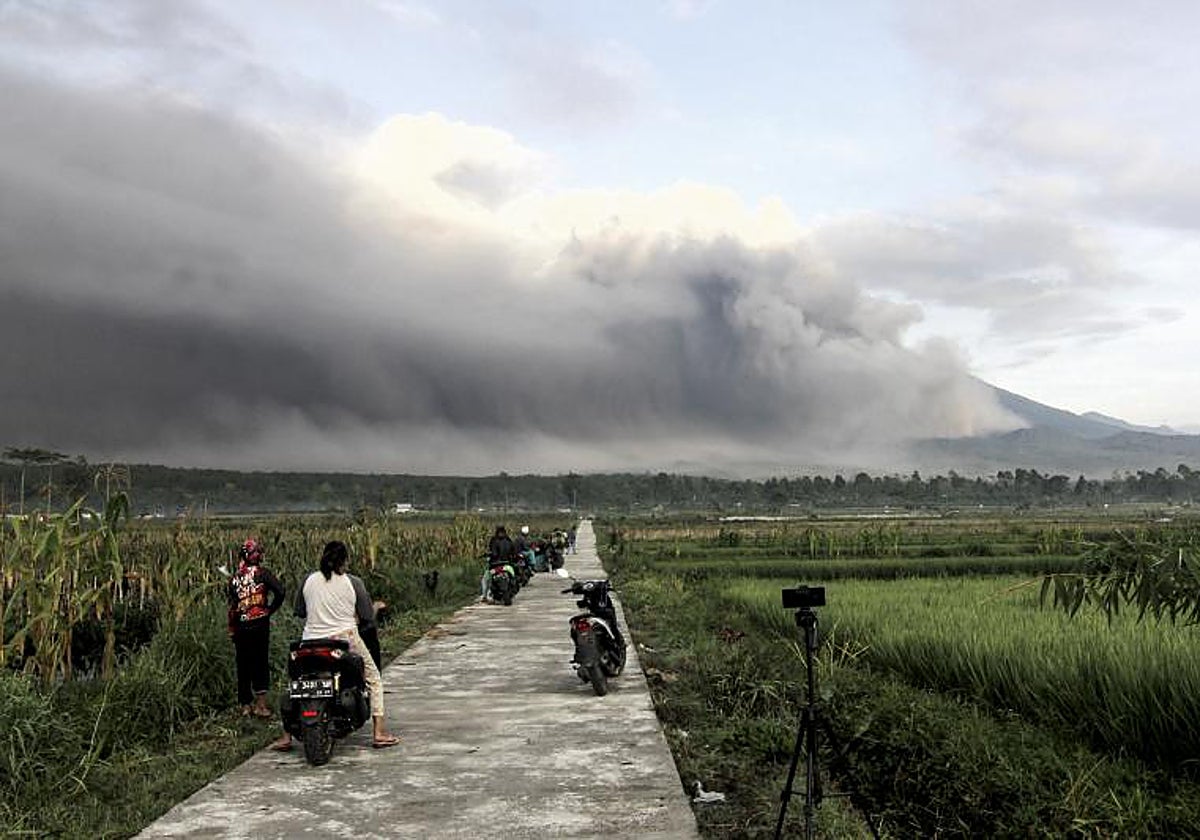 El monte Semeru arroja materiales volcánicos al aire mientras la gente observa durante una erupción en Lumajang, Java Oriental