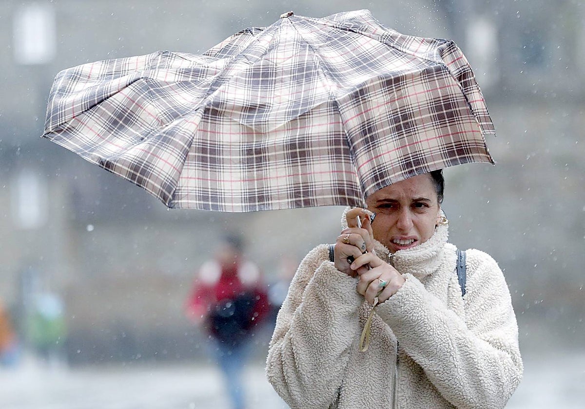 Una mujer lucha por sujetar su paraguas