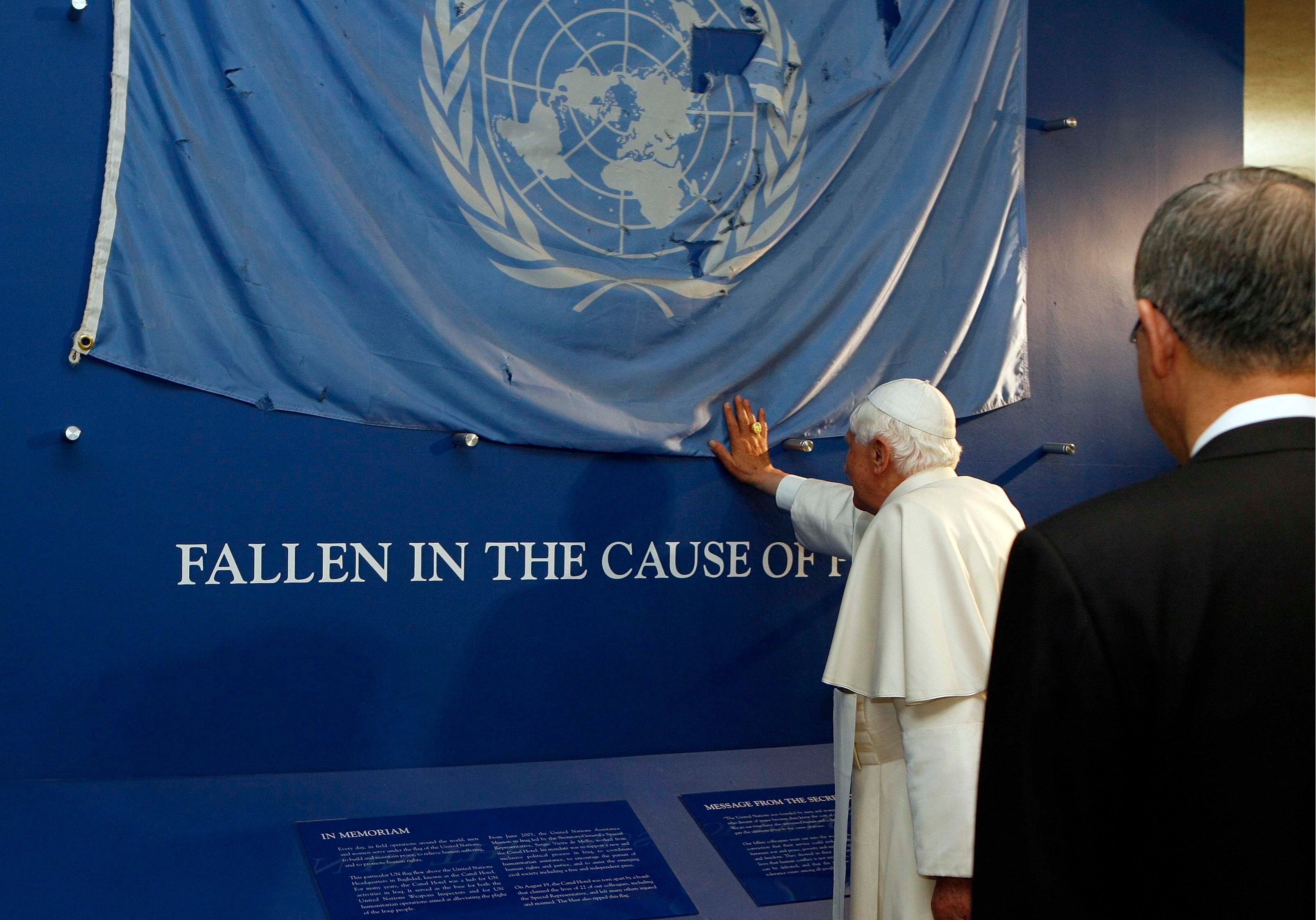 El Secretario General de las Naciones Unidas, Ban Ki-moon, observa al Papa Benedicto XVI tocar y bendecir una bandera de la ONU en la sede de la ONU en Nueva York el 18 de abril de 2008.