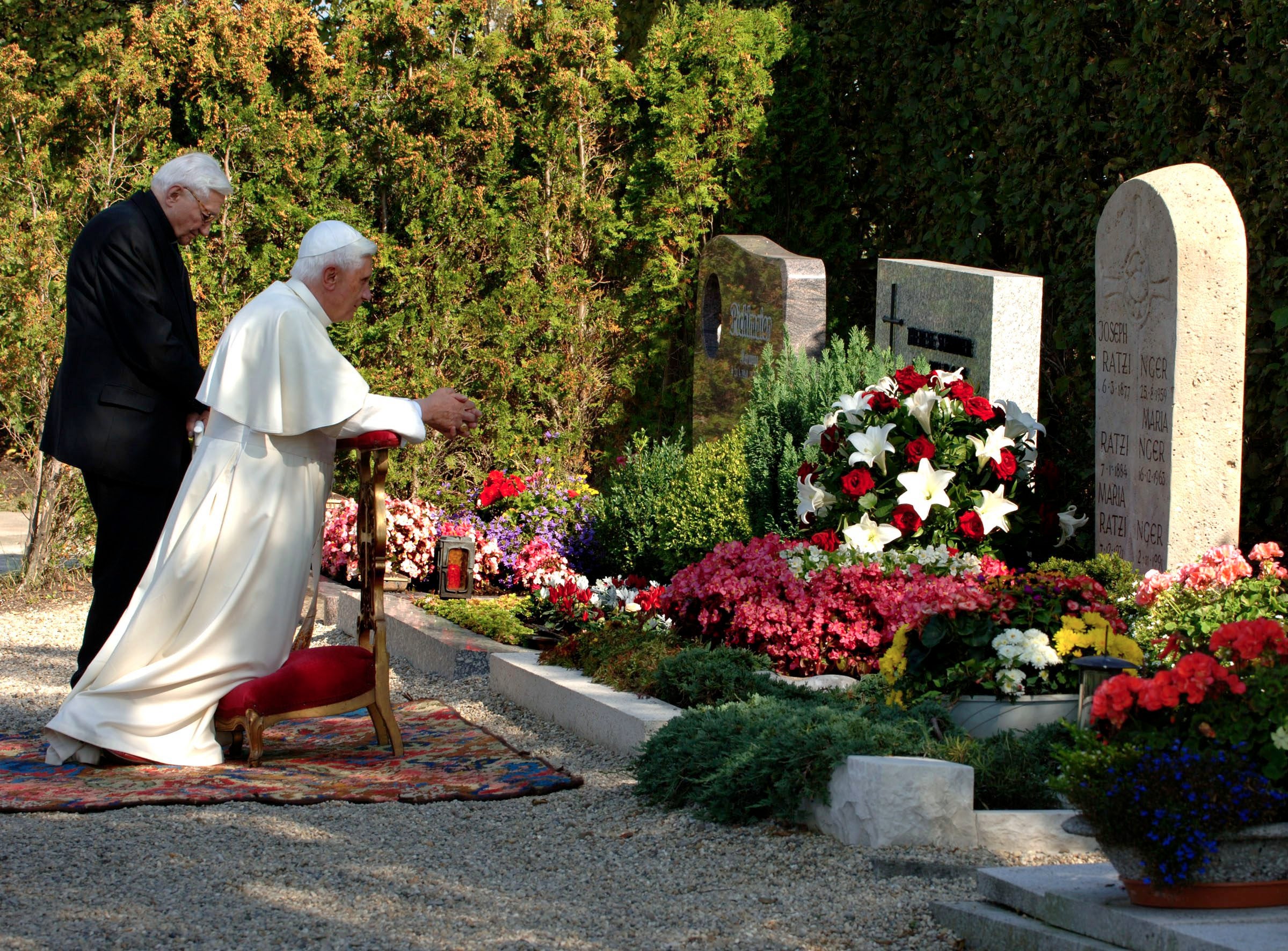 El Papa Benedicto XVI se arrodilla mientras él y su hermano, el reverendo Georg Ratzinger, visitan la tumba de sus padres y su hermana en el cementerio de Ziegetsdorf, en las afueras de Ratisbona, en el sur de Alemania, el miércoles 13 de septiembre de 2006.