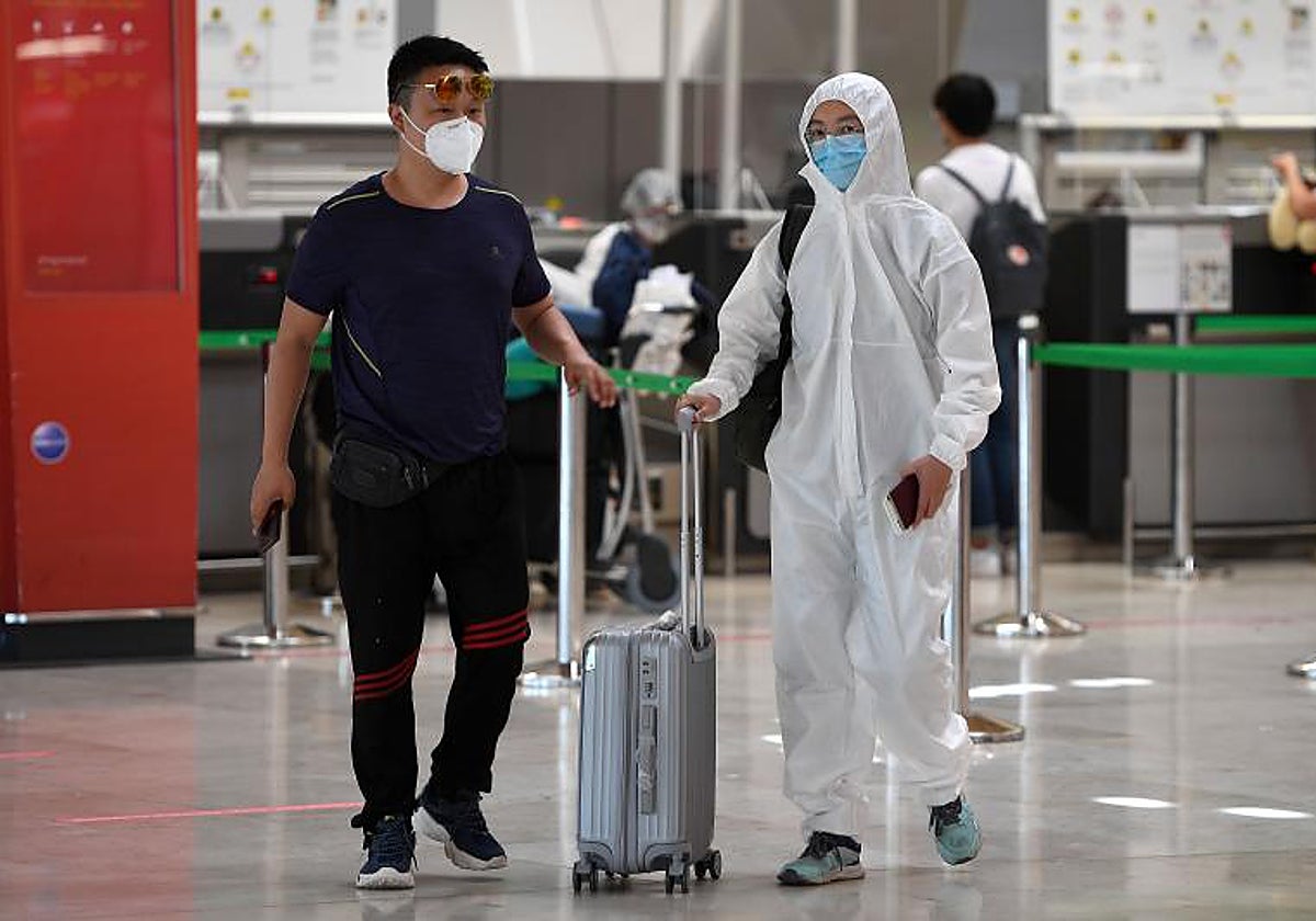 Un pasajero chino ataviado con un traje protector llega al aeropuerto de Madrid procedente de Pekín