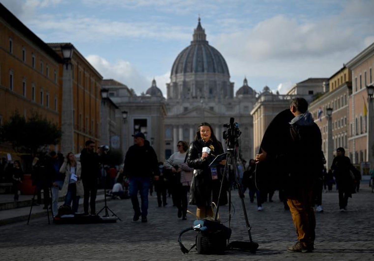 Un periodista se para frente a una cámara, con la Basílica de San Pedro al fondo, tras el anuncio de la muerte del ex Papa Benedicto