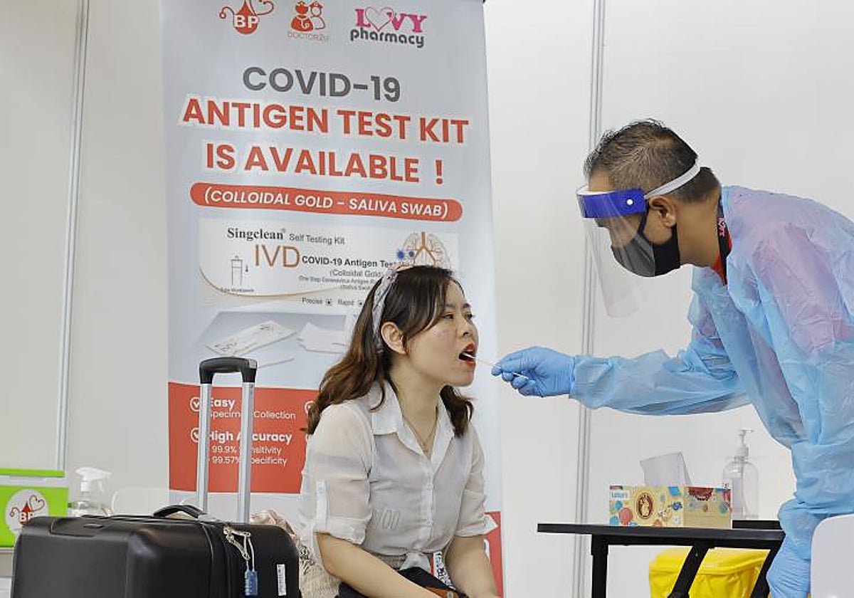 Un sanitario realiza un test de covid a una pasajera, este viernes, en el aeropuerto de Kuala Lumpur, Malasia