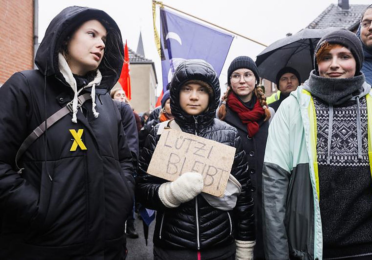 La activista climática sueca Greta Thunberg (C) sostiene un cartel que dice «Luetzi se queda» junto a la activista climática alemana Luisa Neubauer (izq) en una manifestación de activistas de protección climática cerca del pueblo de Luetzerath