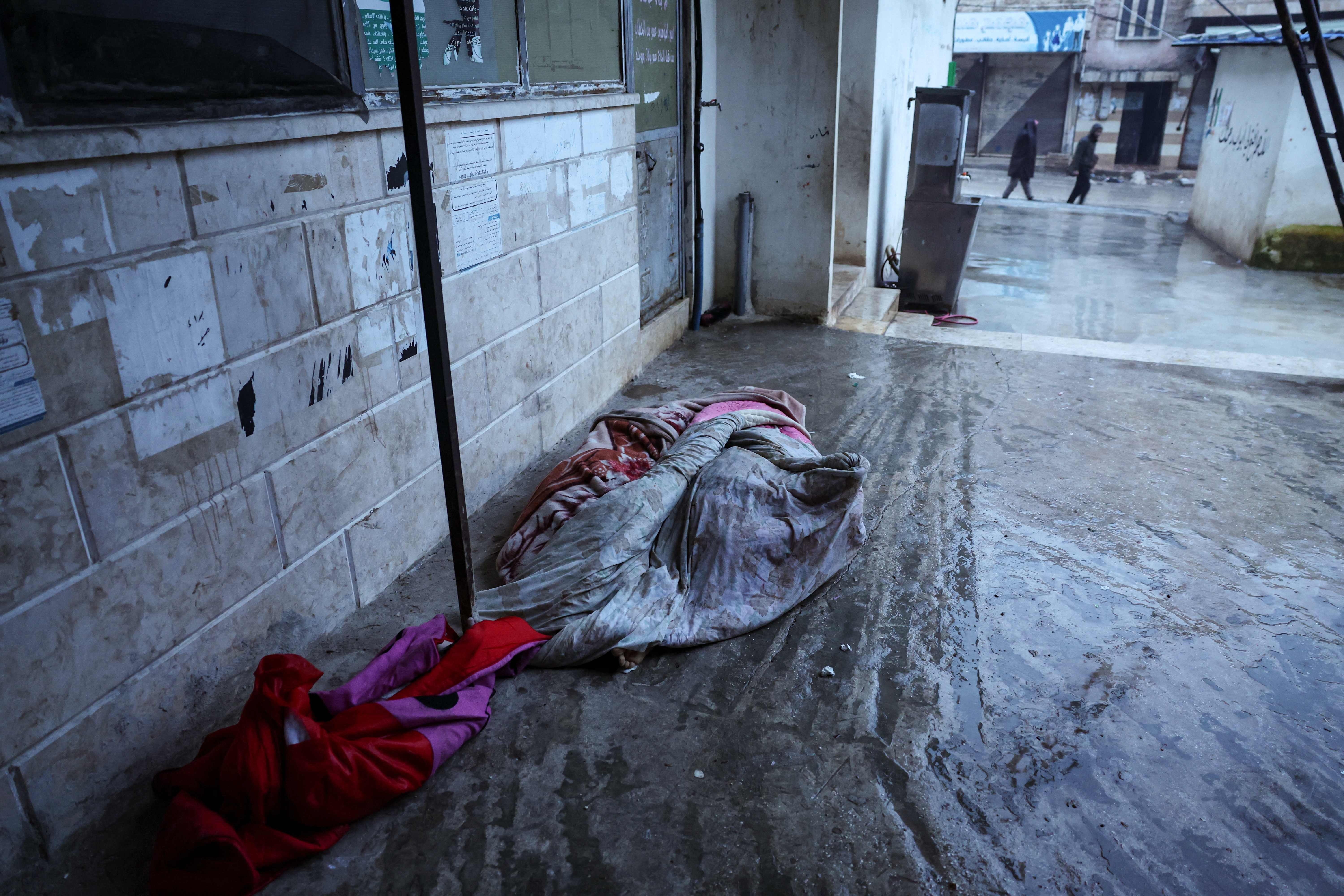 El cadáver de una víctima del terremoto yace al lado de una calle en el pueblo de Azmarin, cerca de la frontera turca en el norte de Siria