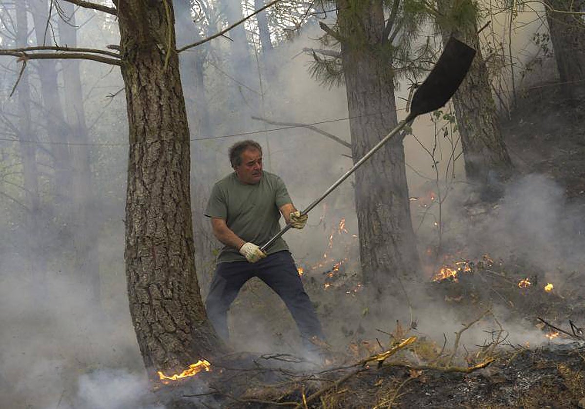 Un hombre trabaja en las labores de extinción del incendio declarado en Navelgas, Asturias