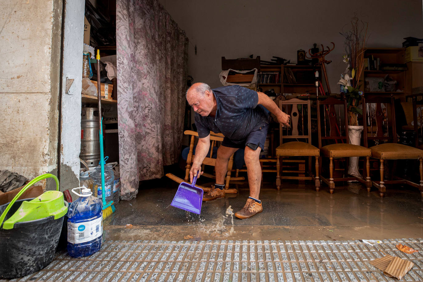 Un vecino del barrio de San Ginés retira el agua de su vivienda