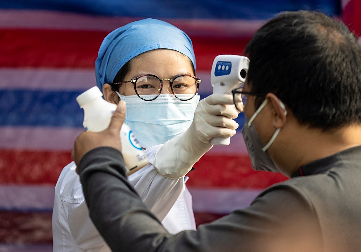 Miembro del personal médico comprueba la temperatura corporal de un ciudadano en China, en una imagen de archivo