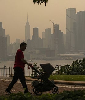 Imagen secundaria 2 - Varias personas permanecen en un parque mientras el horizonte de Nueva York se cubre de bruma y humo procedentes de Canadá