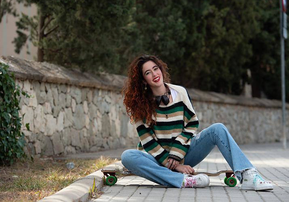 Berta, a las puerta de su colegio, sentada sobre su skate