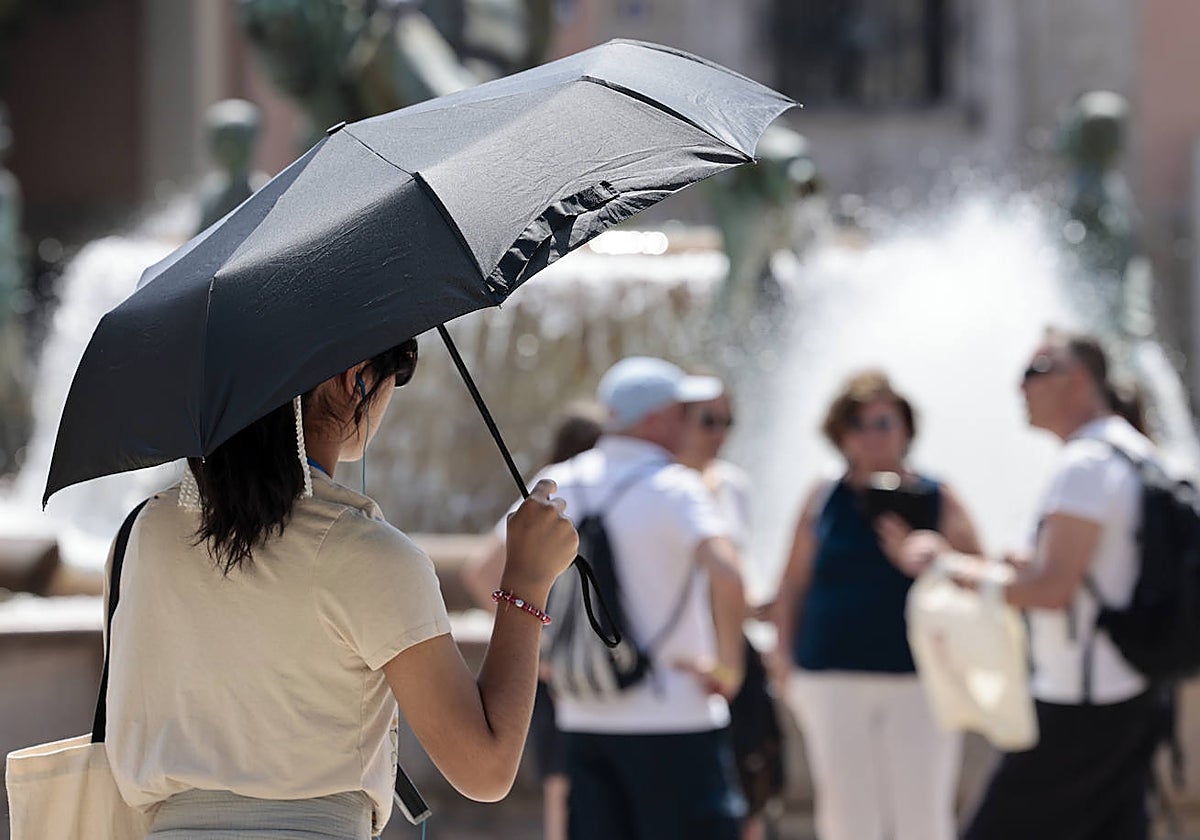 Una joven se protege del sol con una sombrilla en el centro de la ciudad de Valencia