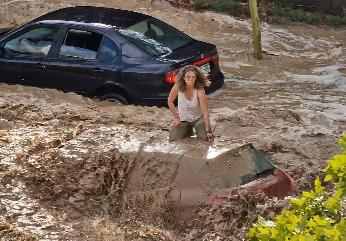 Una mujer se refugia en el techo de un coche durante la tormenta en Zaragoza