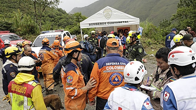 Integrantes de la Defensa Civil, la Cruz Roja y los bomberos se reúnen en una zona afectada por el alud