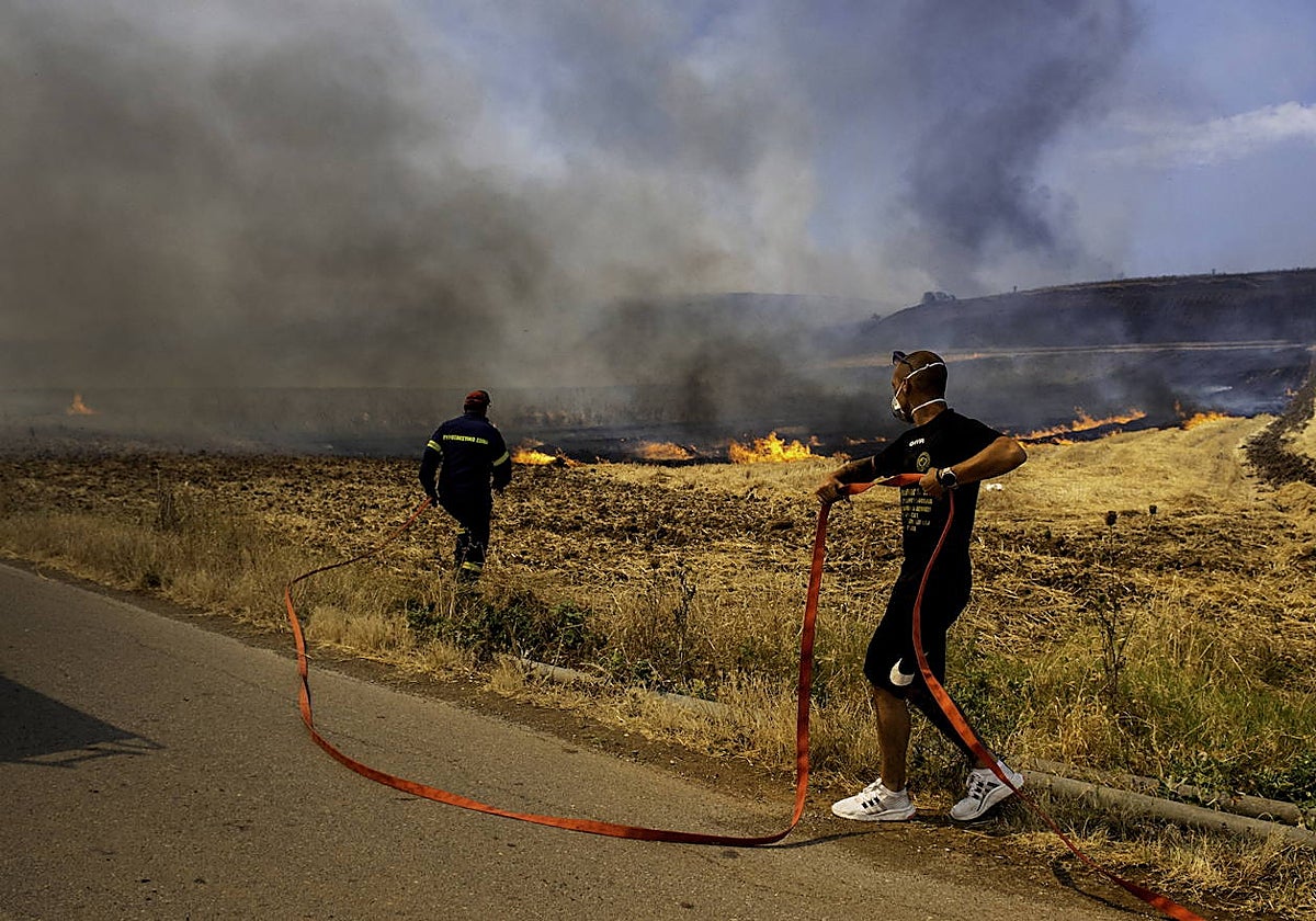 Un bombero y un voluntario apagan un incendio forestal en Velestino, prefectura de Magnesia, Grecia