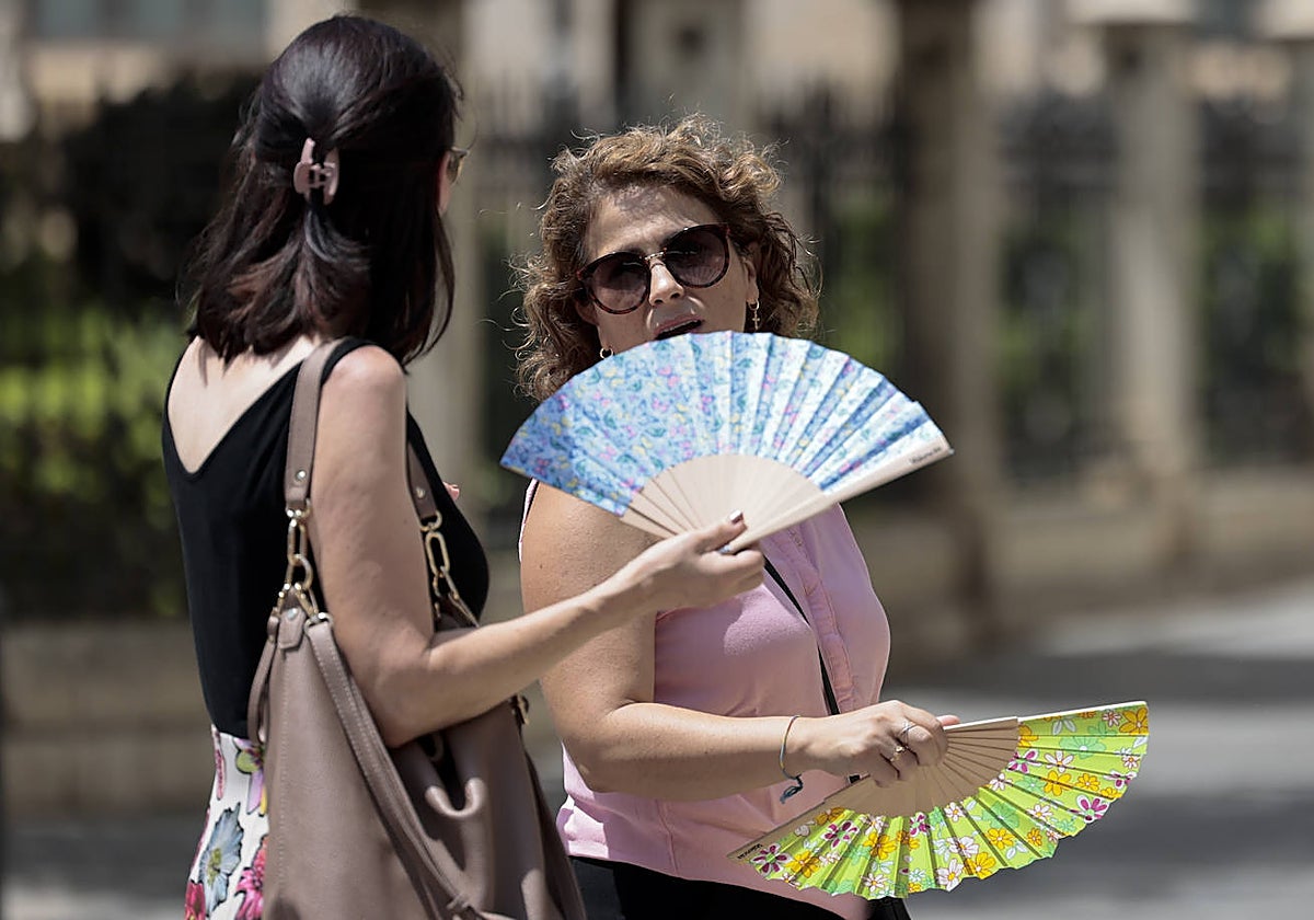 Dos mujeres combaten las altas temperaturas con abanicos