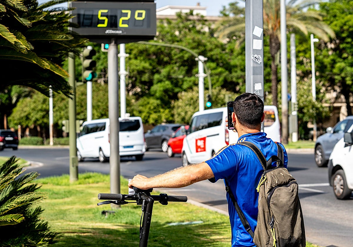 Un turista fotografía un termómetro que marca 52 grados en Sevilla