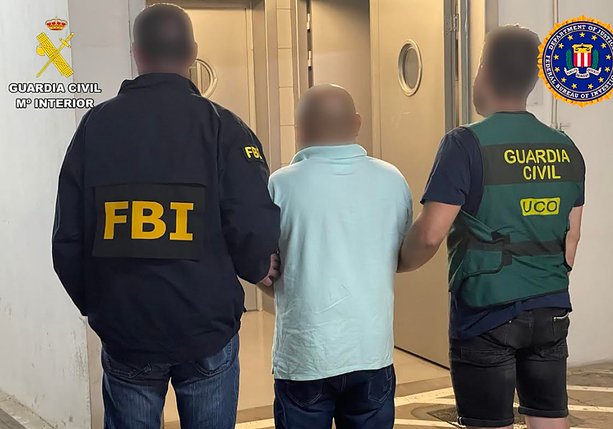 Un agente del FBI y de la Guardia Civil con uno de los detenidos