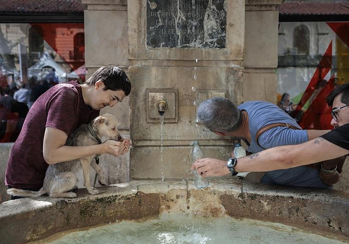 Varias personas se refrescan en una fuente en la localidad valenciana de Xàtiva