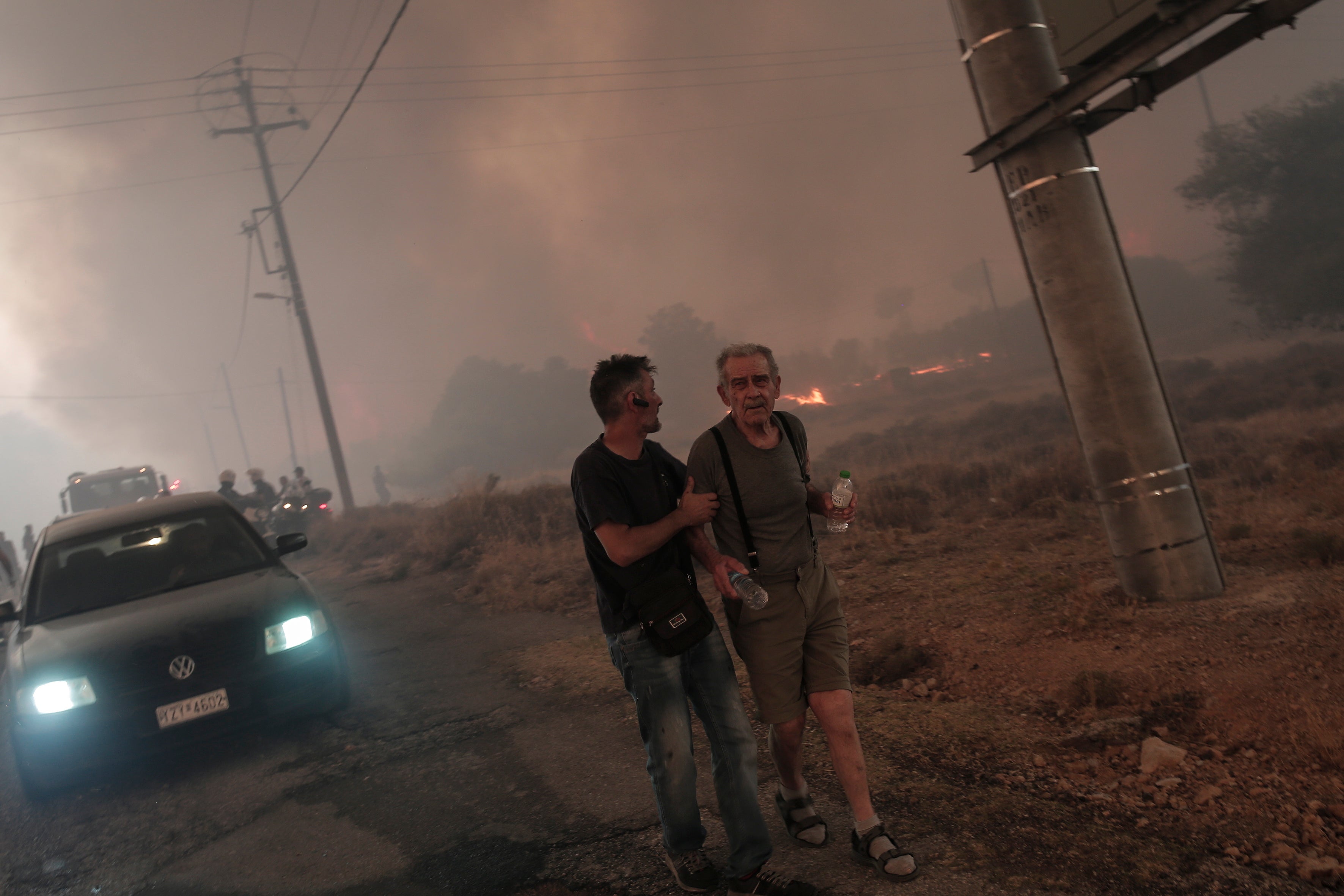 Un residente local evacua a una persona durante el incendio en la zona de Fyli, cerca de Atenas 