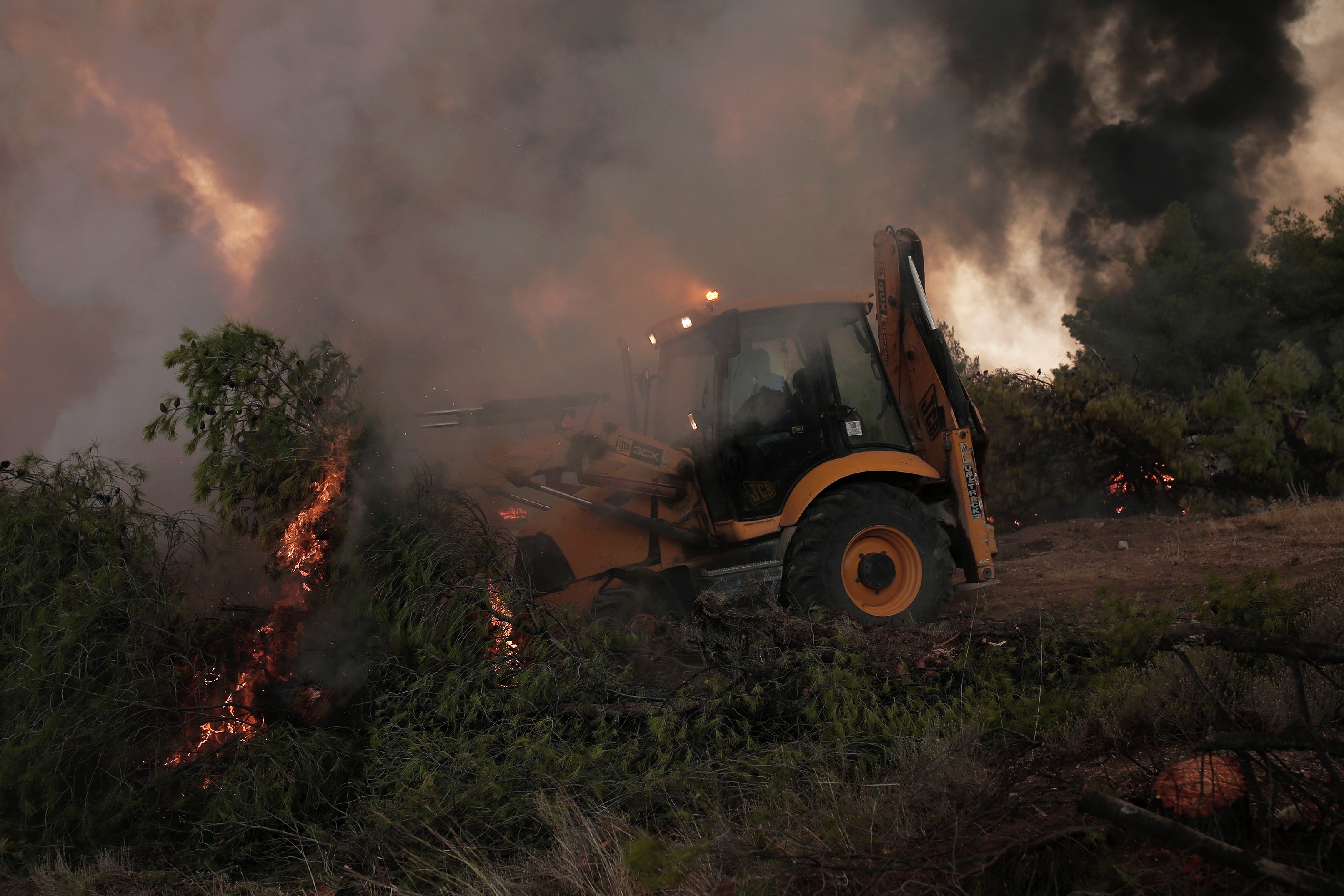Un ciudadano con una excavadora mientras lucha contra las llamas de un incendio en la zona de Fyli, cerca de Atenas 