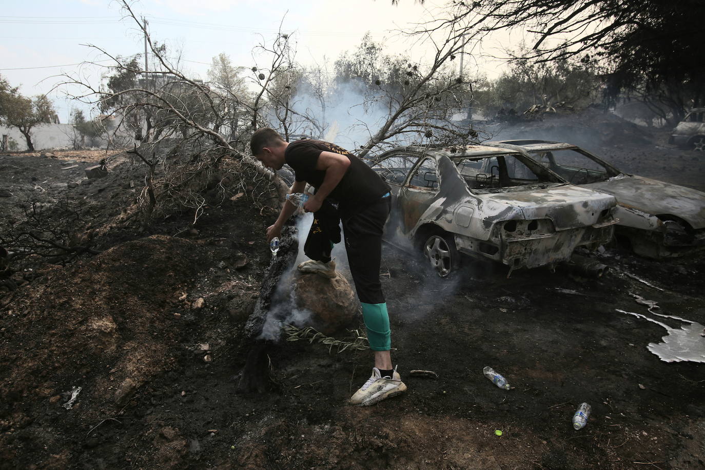 Un voluntario intenta apagar un tronco en llamas en la aldea de Agia Paraskevi (Grecia)
