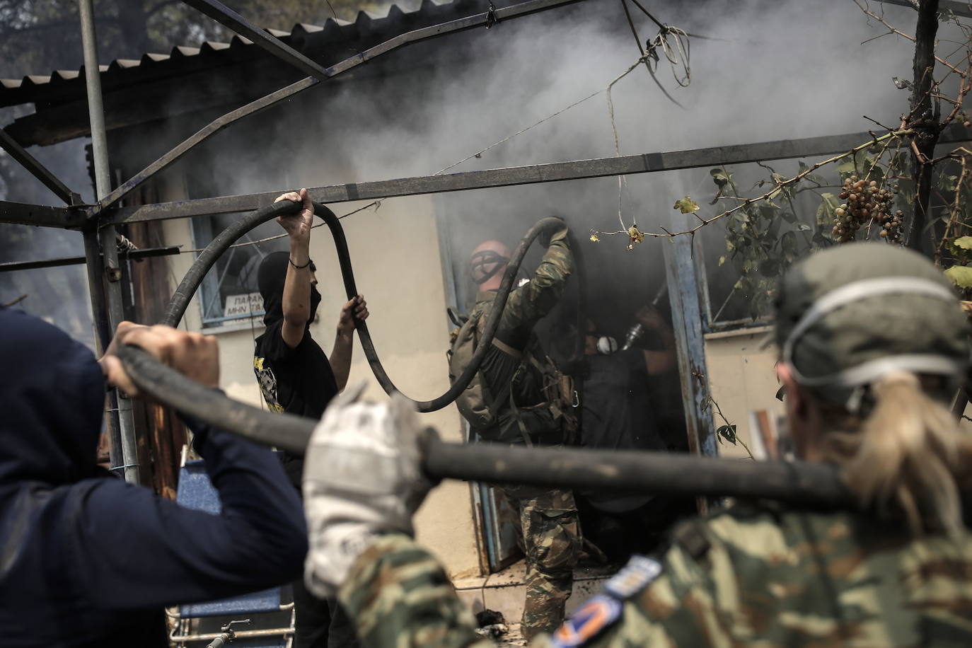 Voluntarios locales intentan extinguir un incendio en una zona residencial situada al pie de la montaña Parnitha, en las afueras de Atenas