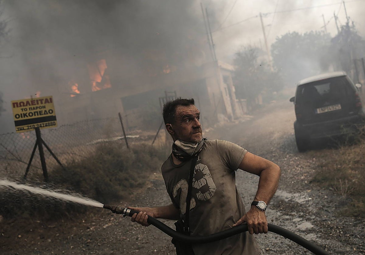 Un residente local lucha contra las llamas en una zona residencial, en las afueras de Atenas