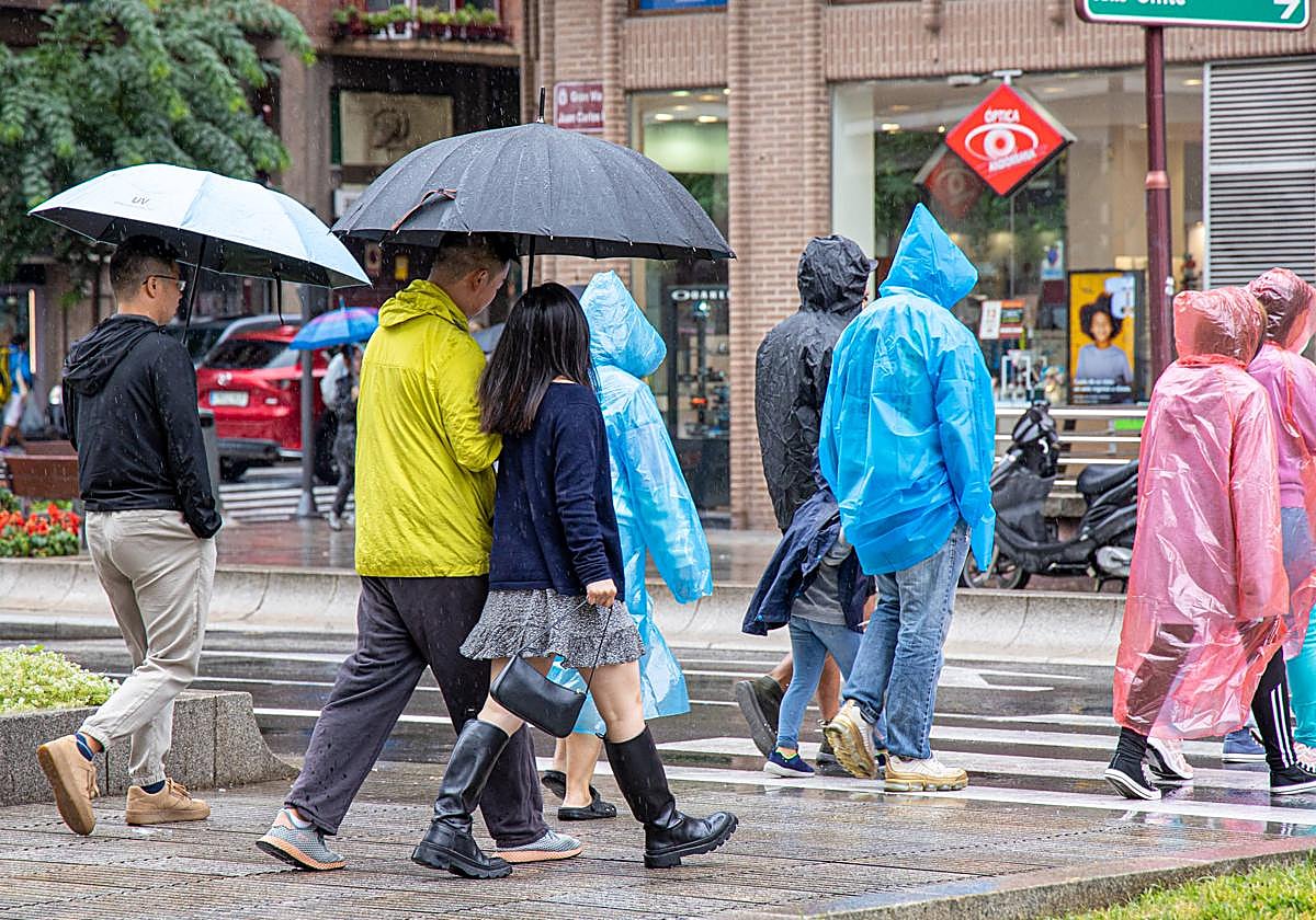 Varios transeúntes caminando bajo la lluvia en Logroño