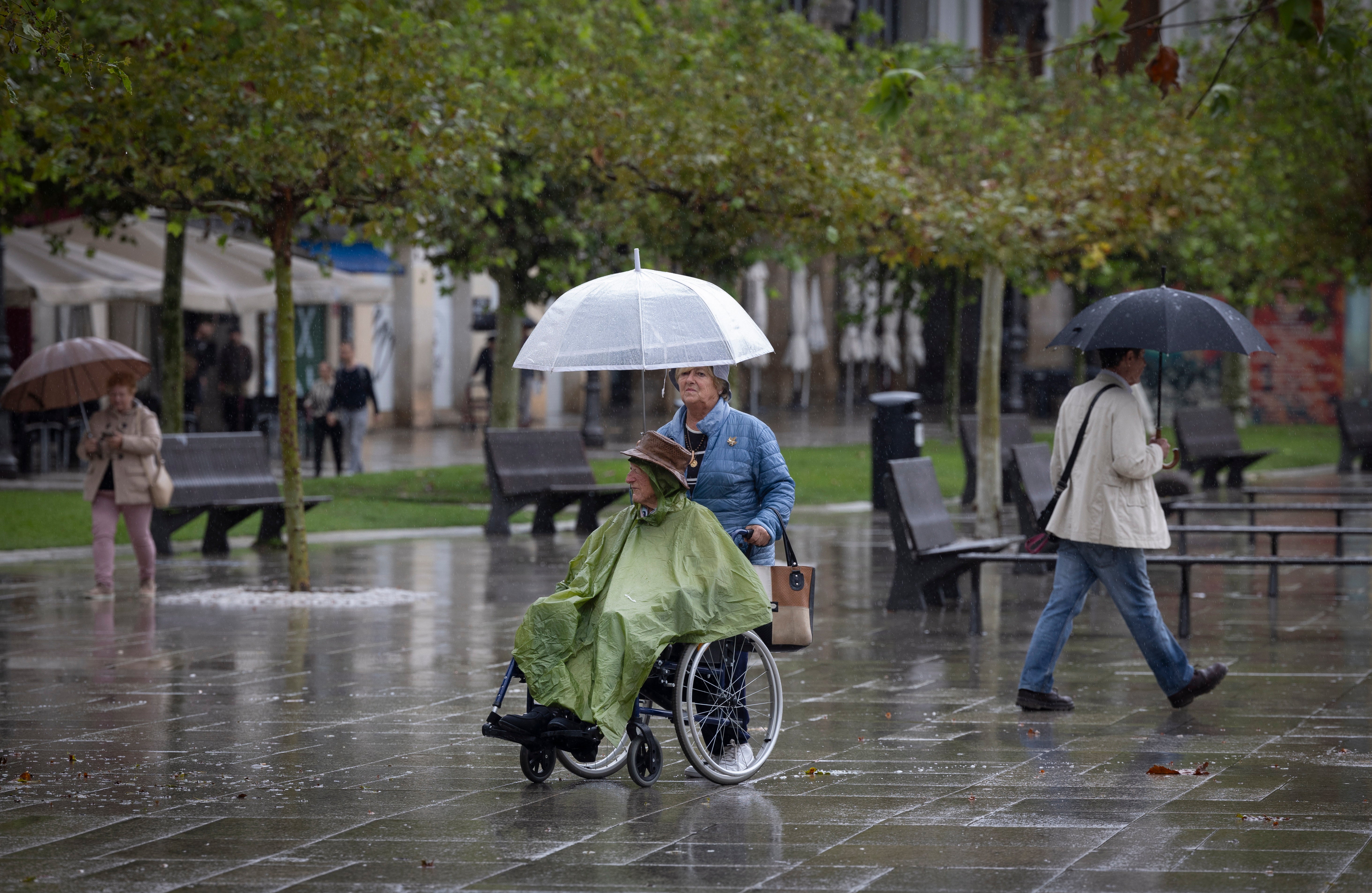 Varias personas caminando bajo la lluvia por Pamplona. 