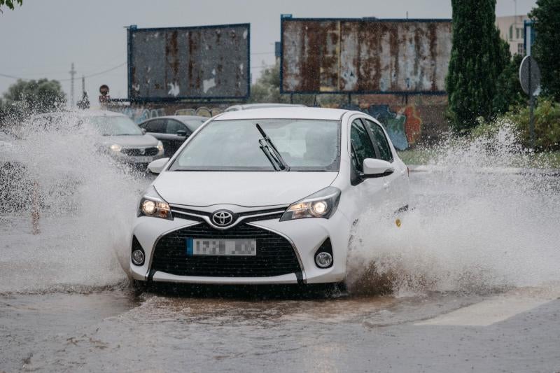 Un coche circula bajo la lluvia