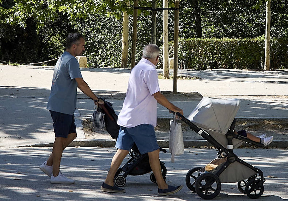 Dos padres pasean a sus hijos en el Parque de El Retiro, Madrid