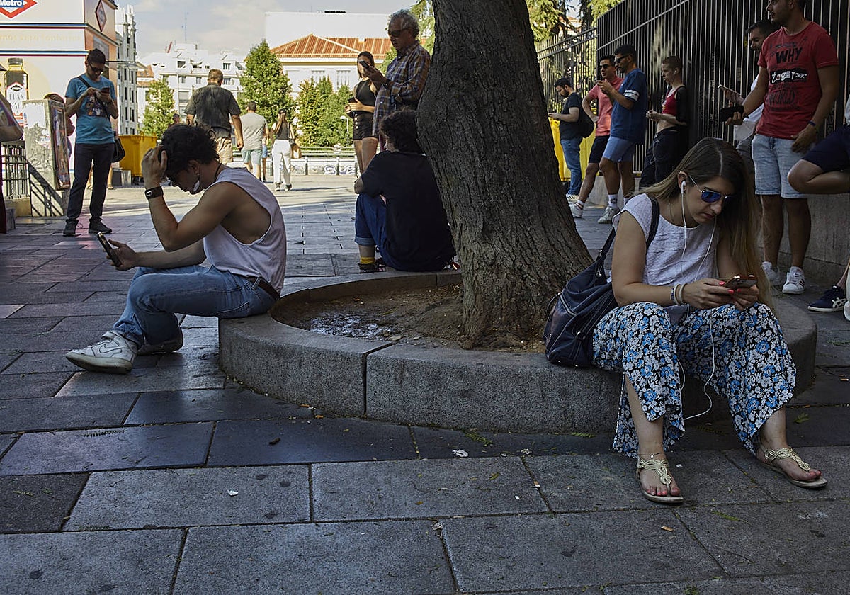Varios jóvenes consultan su teléfono móvil