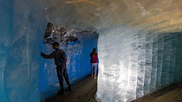 Los visitantes caminan en una cueva de hielo dentro del glaciar del Ródano