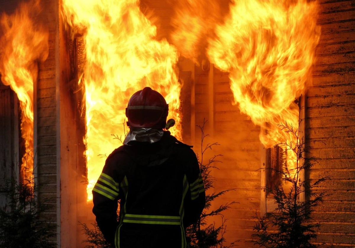 Un bombero frente a una casa en llamas