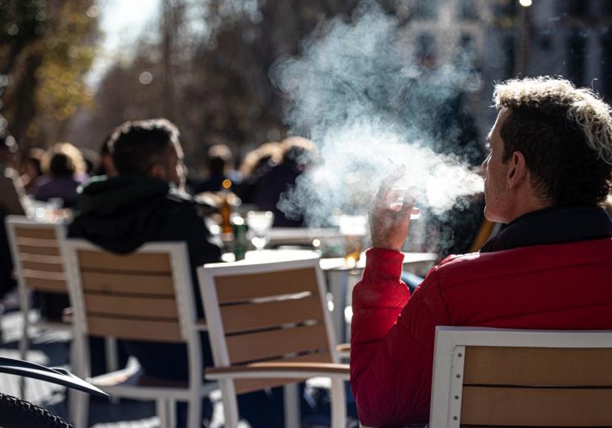 Un hombre fuma un cigarro en una terraza de un bar de Madrid