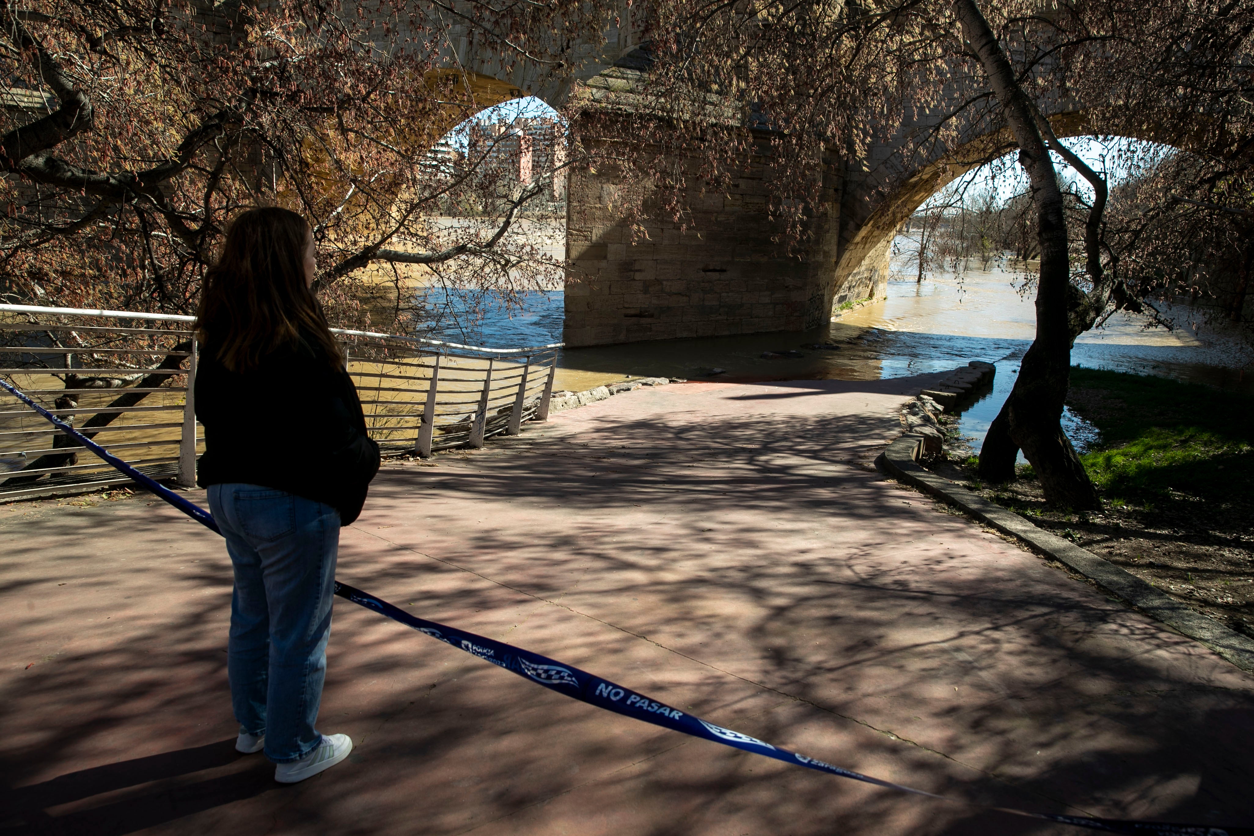 Una mujer observa la crecida del río Ebro a su paso por Zaragoza.