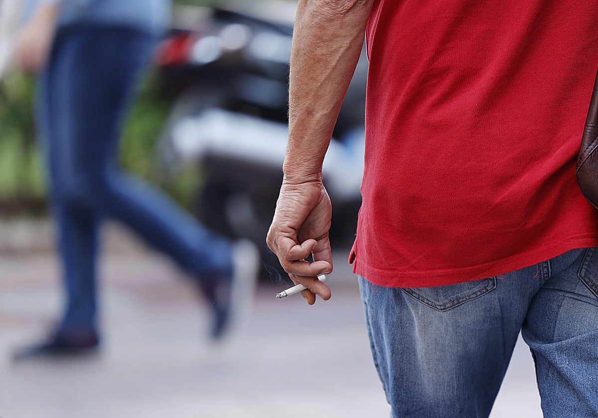 Un hombre fuma un cigarro mientras anda por la calle