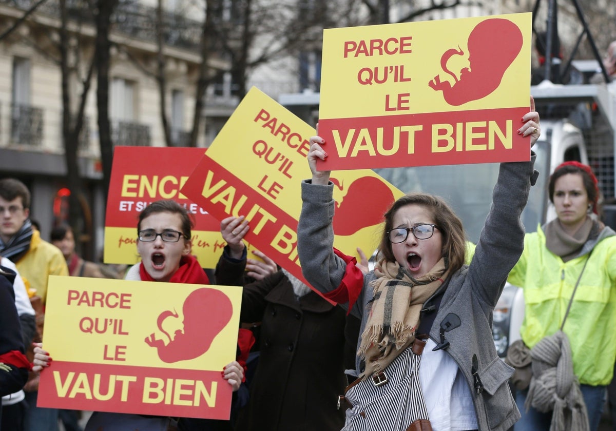 Unas jóvenes portan pancartas mientras asisten a la marcha de protesta contra el aborto 'Marche Pour la Vie' antes de la votación de una enmienda en la Asamblea Nacional de París