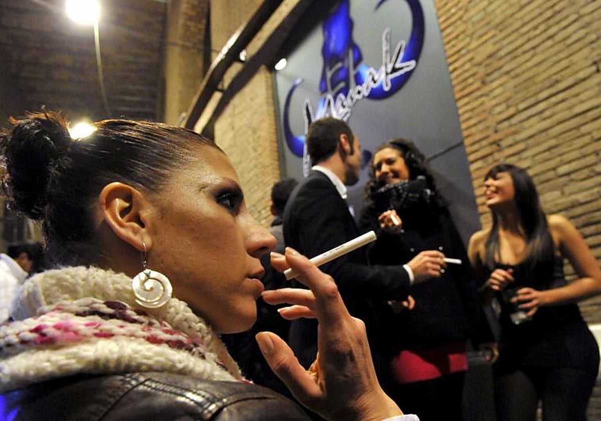 Una joven fuma a la puerta de un bar en Granada