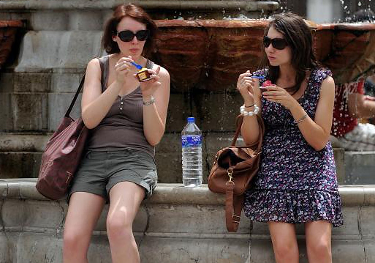 Dos turistas se toman un helado para aliviar las altas temperaturas en la calle