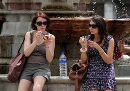 Dos turistas se toman un helado para aliviar las altas temperaturas en la calle