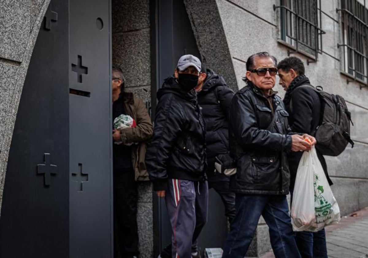 Un grupo de personas recogen bolsas de alimentos en una parroquia de Madrid