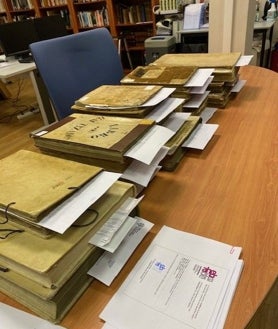 Imagen secundaria 2 - Un momento del proceso de transcripción digital de la partida de nacimiento contenida en uno de los libros en el archivo de la Iglesia en Vizcaya, en la foto superior. Debajo, las tres archiveras encargadas de esta institución, una de las pocas que tiene indexados los archivos hasta 1900. En el detalle, varios libros y junto a las partidas que han sido transcritas. 