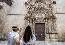 Una pareja de turistas admira la fachada del colegio Montesión en Palma de Mallorca