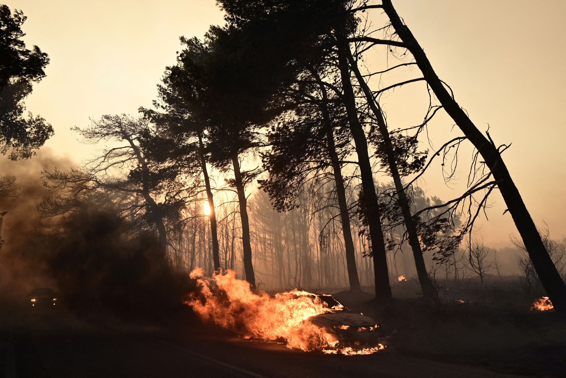 Un coche, consumido por las llamas que rodean Atenas